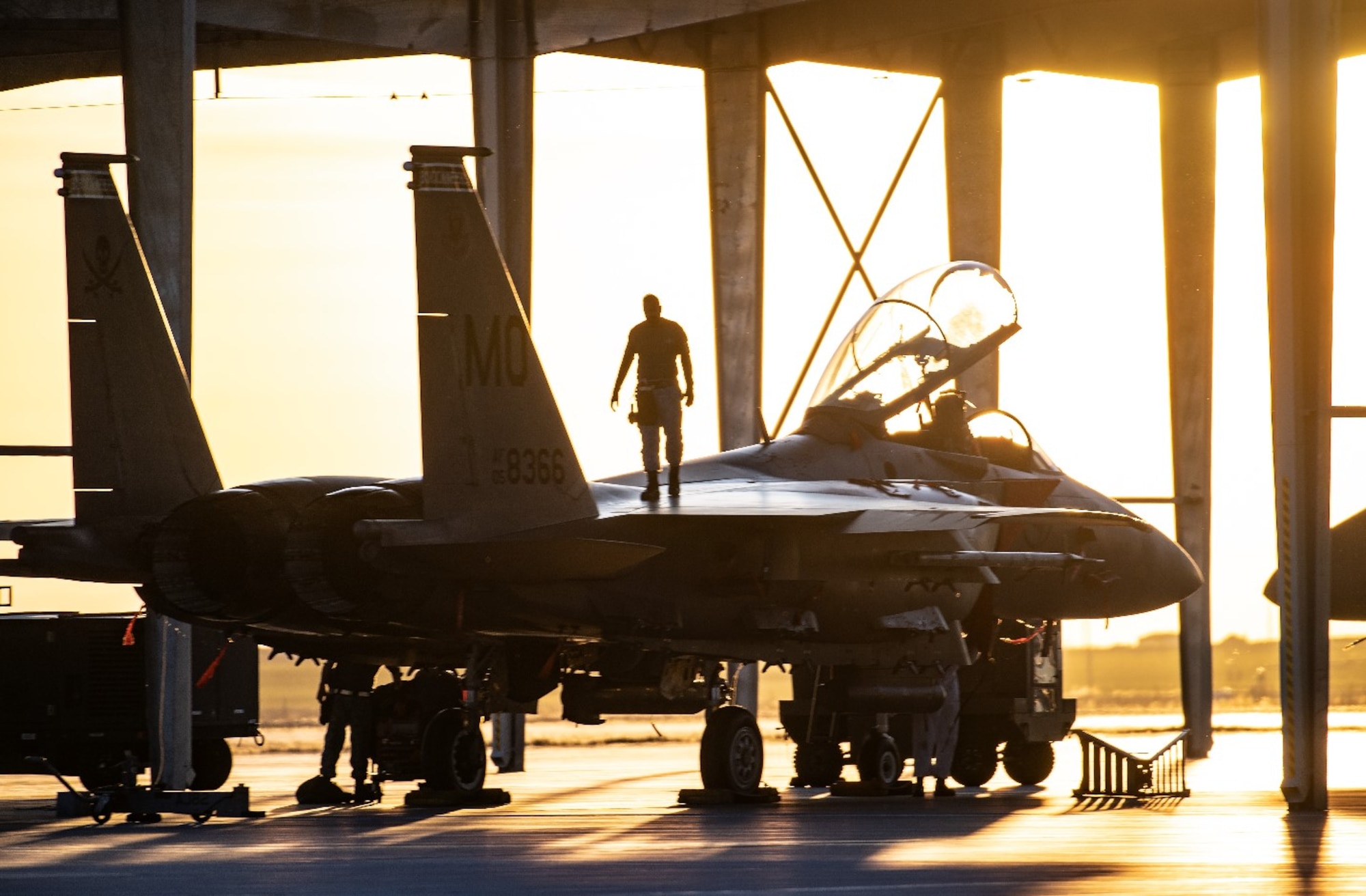 An Airman from Mountain Home Air Force Base, Idaho, surveys an F-15SG Strike Eagle April 28, 2021, on the Mountain Home AFB flight line. The F-15 participated in exercise Rainier War, testing its ability to employ air combat capabilities during a time of potentially imminent foreign aggression.