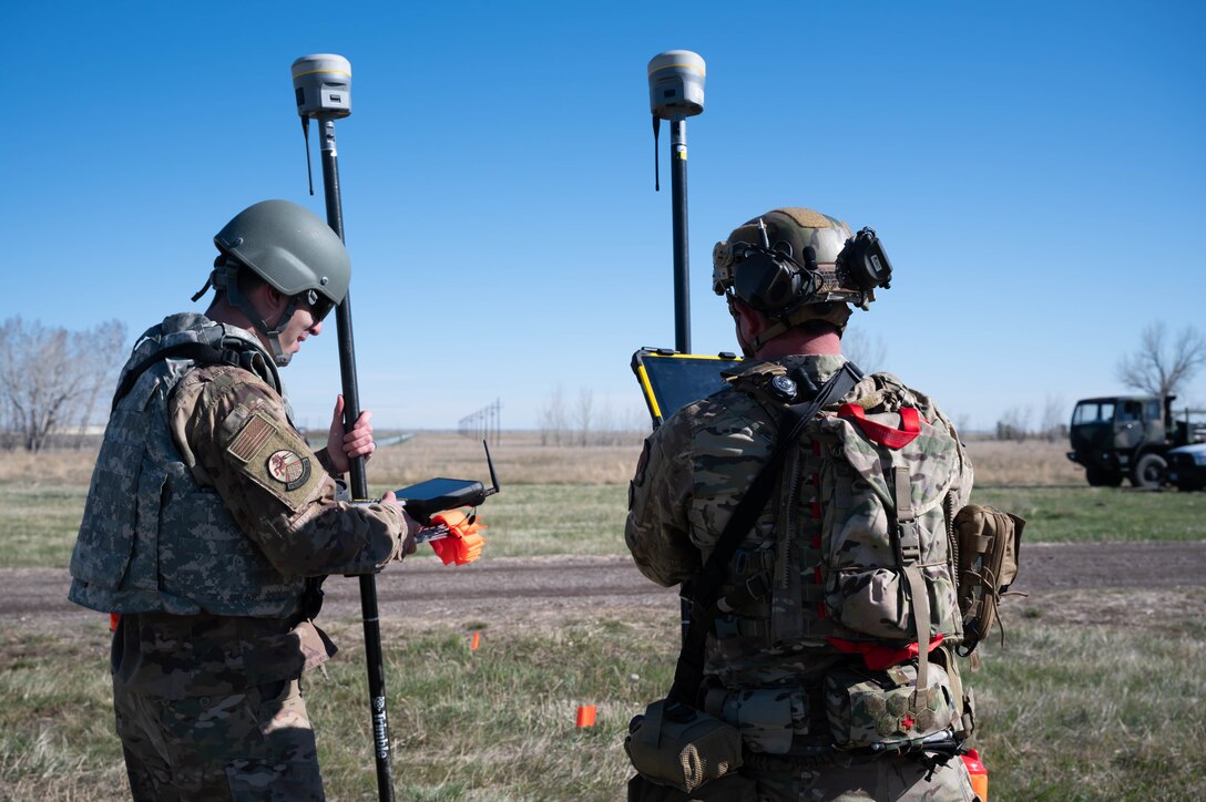 Staff Sgt. Christopher D'Amata, left, and Tech. Sgt. Benjamin Hammond, 819th RED HORSE Squadron engineering technicians, use a survey-grade global positioning satellite device to plot the locations where structures will be built during an exercise May 3, 2021, at Malmstrom Air Force Base, Mont.