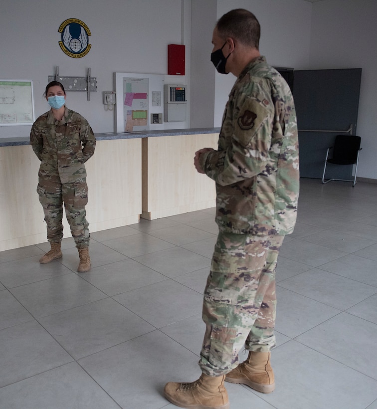 Male Colonel congratulates female Airman on award.