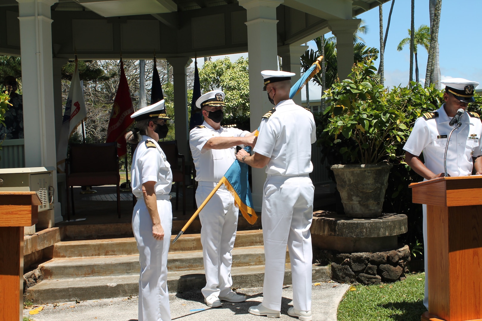 A Navy commander accepts a flag from a Navy captaind