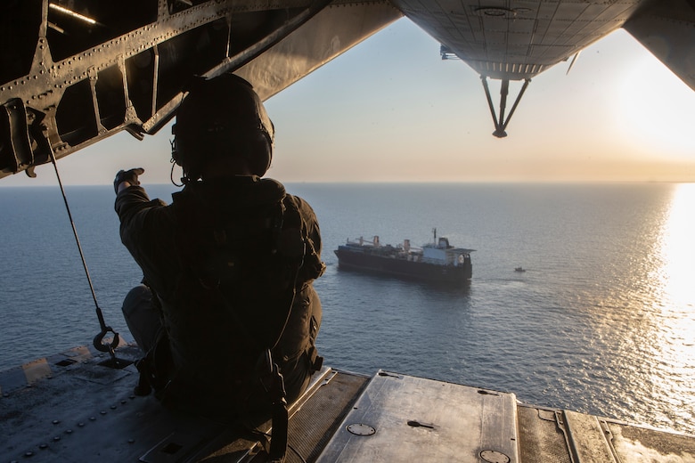 A U.S. Marine sits on the CH-53E Super Stallion’s ramp as the aircraft leaves the USNS D. T. Williams (T-AK-3009), April 5.
