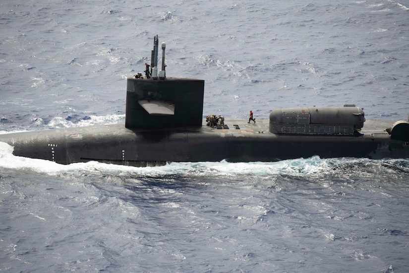 Marines work atop a submarine.