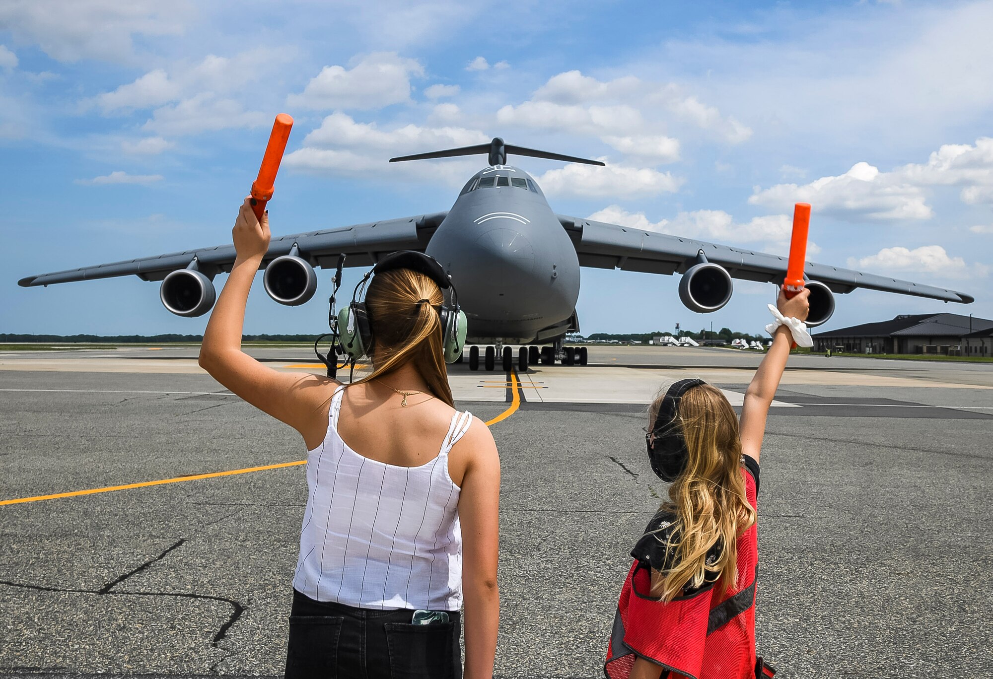Devyn Jones, left, and Brooke Jones, marshal in a C-5M Super Galaxy piloted by their father, Col. Matthew Jones, 436th Airlift Wing commander, after his fini flight at Dover Air Force Base, Delaware, May 4, 2021. A “fini flight” is an Air Force tradition where an Airman and their family celebrate their final flight. (U.S. Air Force photo by Airman 1st Class Stephani Barge)
