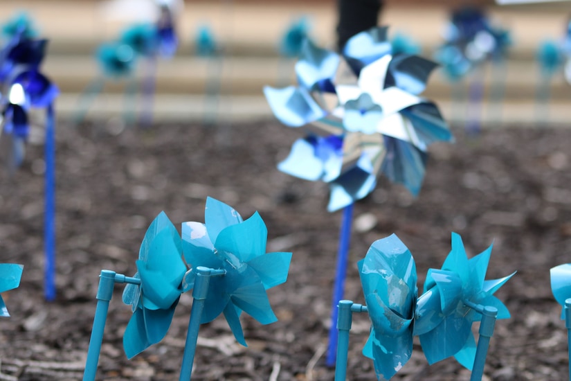 Teal and blue colored pinwheels in the ground.