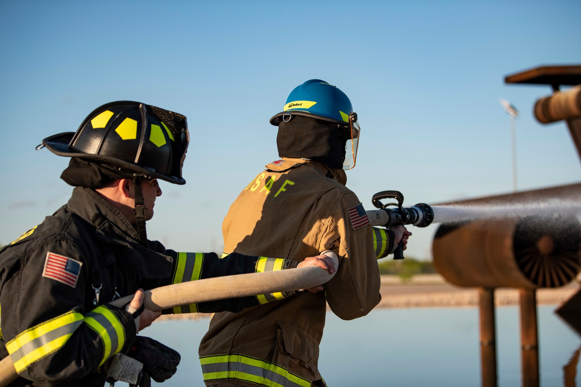 Senior Airman Jarrett Ziegler, 512th Civil Engineer Squadron firefighter, left, and Airman 1st Class Andrew Trujillo, 7th CES firefighter, test a firehose at Dyess Air Force Base, Texas, May 4, 2021. Zieglar and Trujillo conducted a routine function test of the firehose to ensure it was operating properly before conducting an aircraft fire training. (U.S. Air Force photo by Airman 1st Class Colin Hollowell)