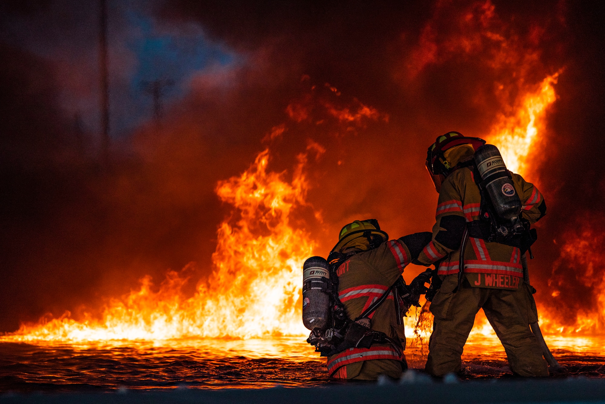 An Abilene Regional Airport aircraft rescue team firefighter helps another aircraft rescue team firefighter to his feet during an aircraft fire training at Dyess Air Force Base, Texas, May 4, 2021. Members of the  Abilene Regional Airport aircraft rescue team joined 7th and 512th Civil Engineer Squadron firefighters during the training. Participating in the joint-training provided the firefighters with the opportunity to enhance safety and communication practices. (U.S. Air Force photo by Airman 1st Class Colin Hollowell)