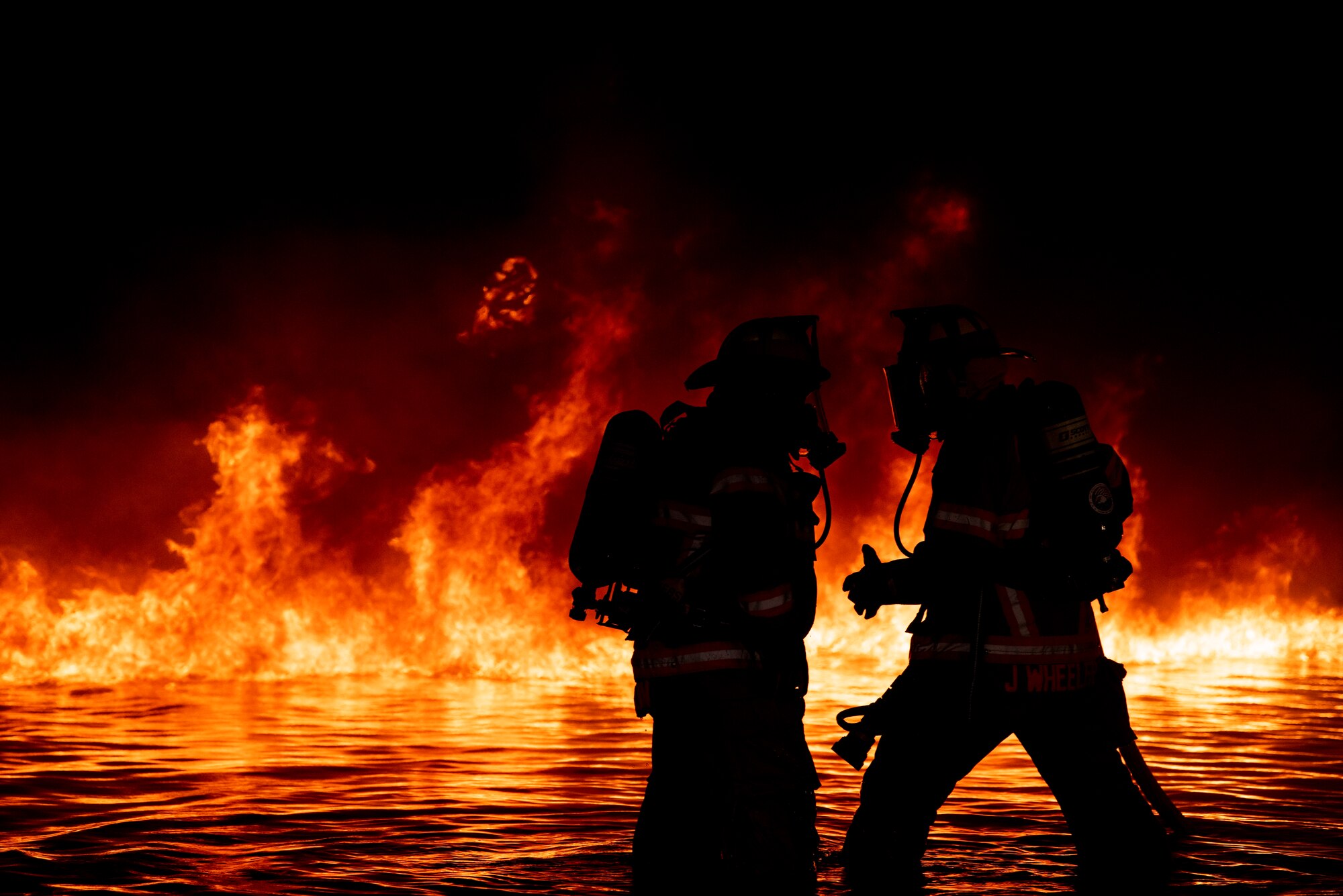 Two Abilene Regional Airport aircraft rescue team firefighters perform wellness checks on one-another during a nighttime aircraft fire training at Dyess Air Force Base, Texas, May 4, 2021. Aircraft fires can reach temperatures of over 1000 degrees Fahrenheit. Safe practices and clear communication while responding to emergencies are crucial to the safety of those who need assistance as well as the responders assisting them. (U.S. Air Force photo by Airman 1st Class Colin Hollowell)