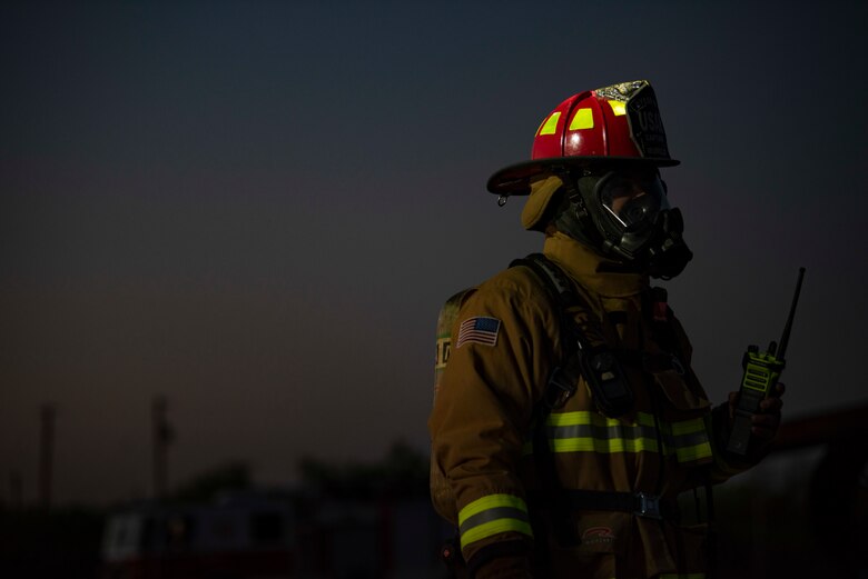 A firefighter assigned to the 7th Civil Engineer Squadron oversees a nighttime aircraft fire training at Dyess Air Force Base, Texas, May 4, 2021. Conducting the aircraft fire training at night tested the firefighters ability to safely combat fires while operating in low-light conditions, enhancing the readiness necessary to respond to fire emergencies 24 hours a day. (U.S. Air Force photo by Airman 1st Class Colin Hollowell)