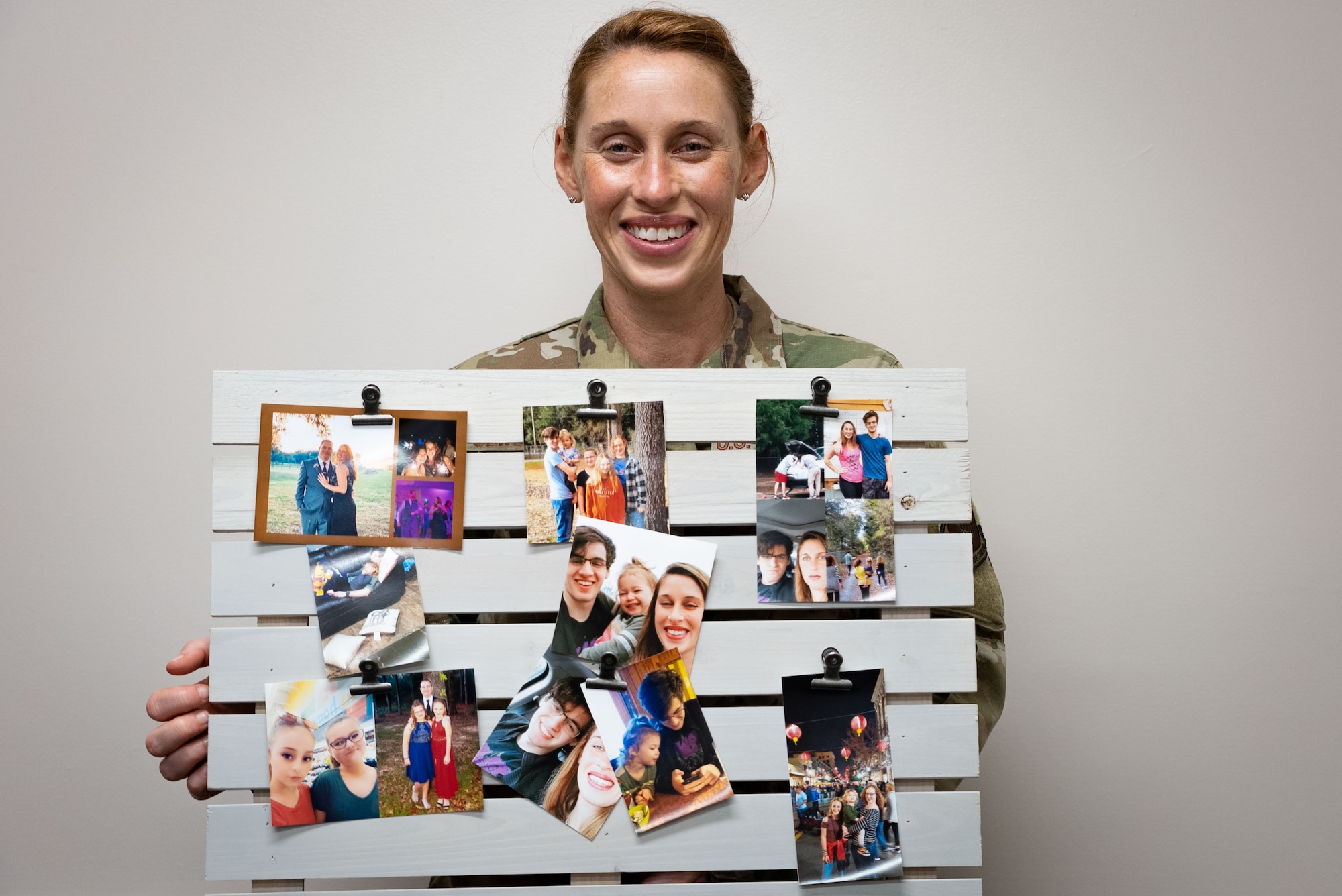 Female Airman hold decorative pallet board with photos of her children attached.