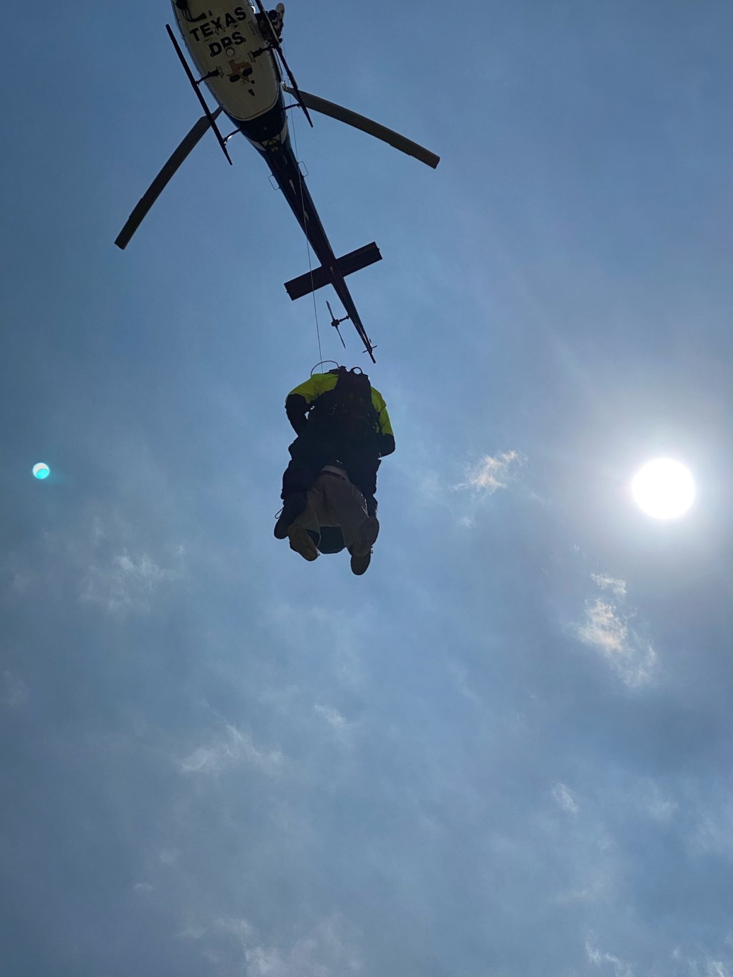 Helicopter hoisting person into the air