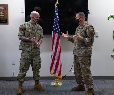 Chief Master Sgt. Steven Koehler, 15th Wing command chief presents a coin to Tech. Sgt. John Westlund, 17th Operational Weather Squadron weather craftsman, for going above and beyond by helping a wingman in need at Joint Base Pearl Harbor-Hickam, Hawaii, May 6, 2021. Westlund was also awarded the Achievement Medal, an award given for meritorious service rendered specifically on behalf of the Air Force. (U.S. Air Force photo by Airman 1st Class Makensie Cooper) (This image was cropped to emphasize the subject.)