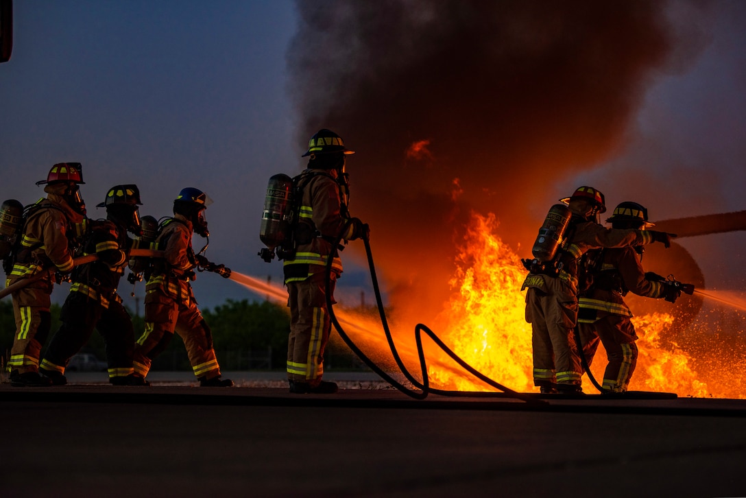 Firefighters assigned to the 7th Civil Engineer Squadron and 512th CES extinguish flames during an aircraft fire training at Dyess Air Force Base, Texas, May 4, 2021. Firefighters assigned to the 7th and 512th CES conducted the live fire training with firefighters from the Abilene Regional Airport’s aircraft rescue team to enhance safety, proficiency and interoperability. (U.S. Air Force photo by Airman 1st Class Colin Hollowell)
