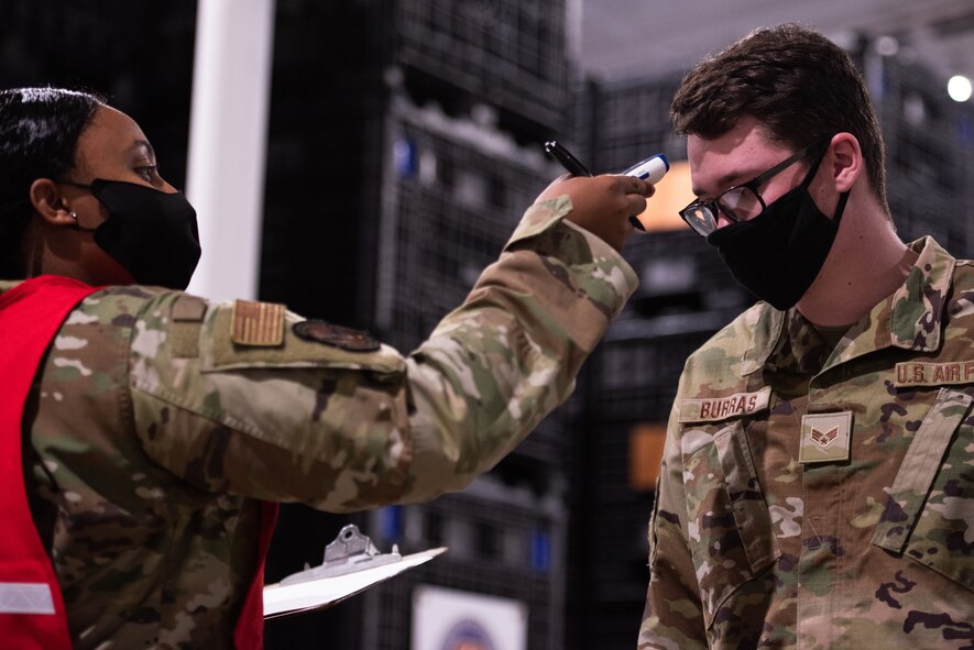 U.S. Air Force Senior Airman Jacquelyn Fleming, 375th Logistics Readiness Squadron personal property councilor, takes the temperature of Senior Airman Logan Burras, 375th Comptroller Squadron server admin, during a mobility exercise on Scott Air Force Base, Illinois, April 28, 2021. The mobility exercise at Scott was an opportunity to simulate deployment processes and ensure mission readiness. (U.S. Air Force photo by Airman 1st Class Isaac Olivera)