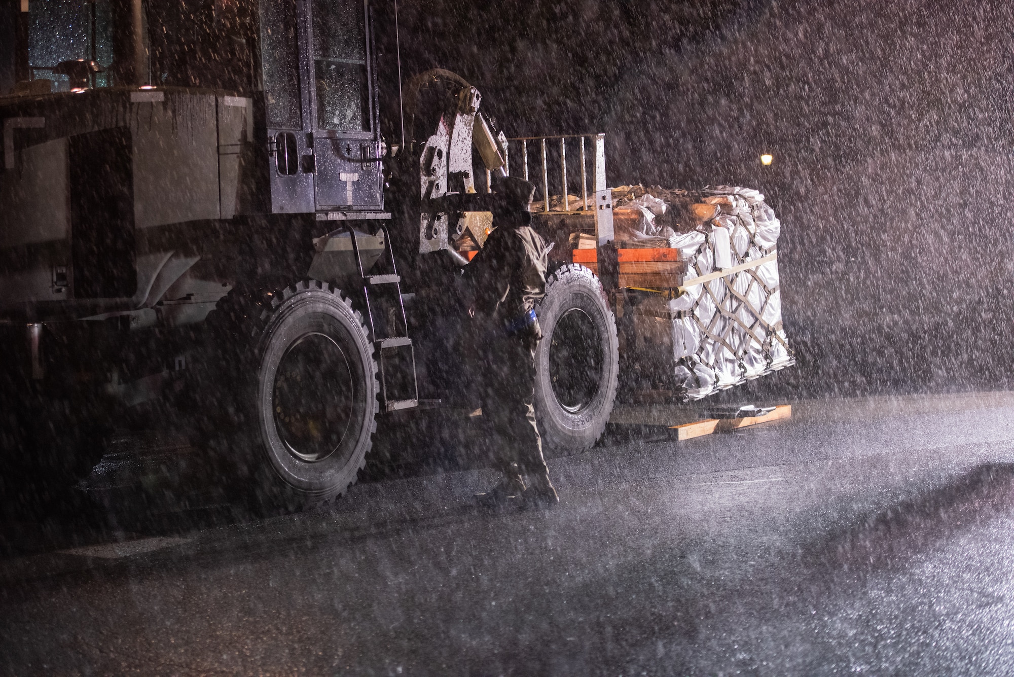 A 375th Logistics Readiness Squadron Airman loads cargo into a cargo port during the mobility exercise on Scott Air Force Base, Illinois, April 28, 2021. The 375th LRS utilized tarps on port cargo to protect against the inclement weather. (U.S. Air Force photo by Airman 1st Class Isaac Olivera)