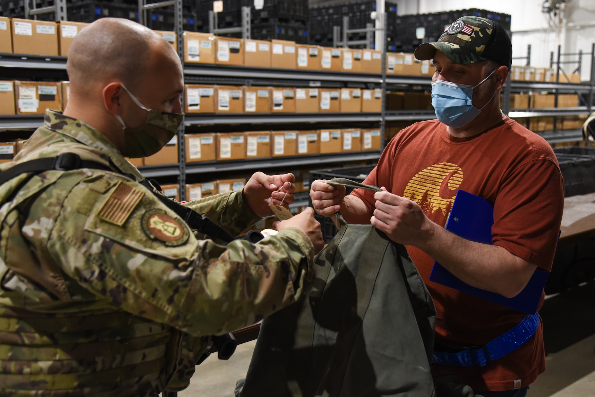 U.S. Air Force Staff Sgt Kyle Dover, 375th Force Support Squadron combat arms instructor holds his deployment bag while an identifying tag is being fastened, on Scott Air Force Base, Illinois, April, 28 2021. During the mobility exercise, Dover received gear that he would need for a deployment like a gas mask, helmet, and gloves. (U.S. Air Force photo by Airman 1st Class Mark Sulaica)