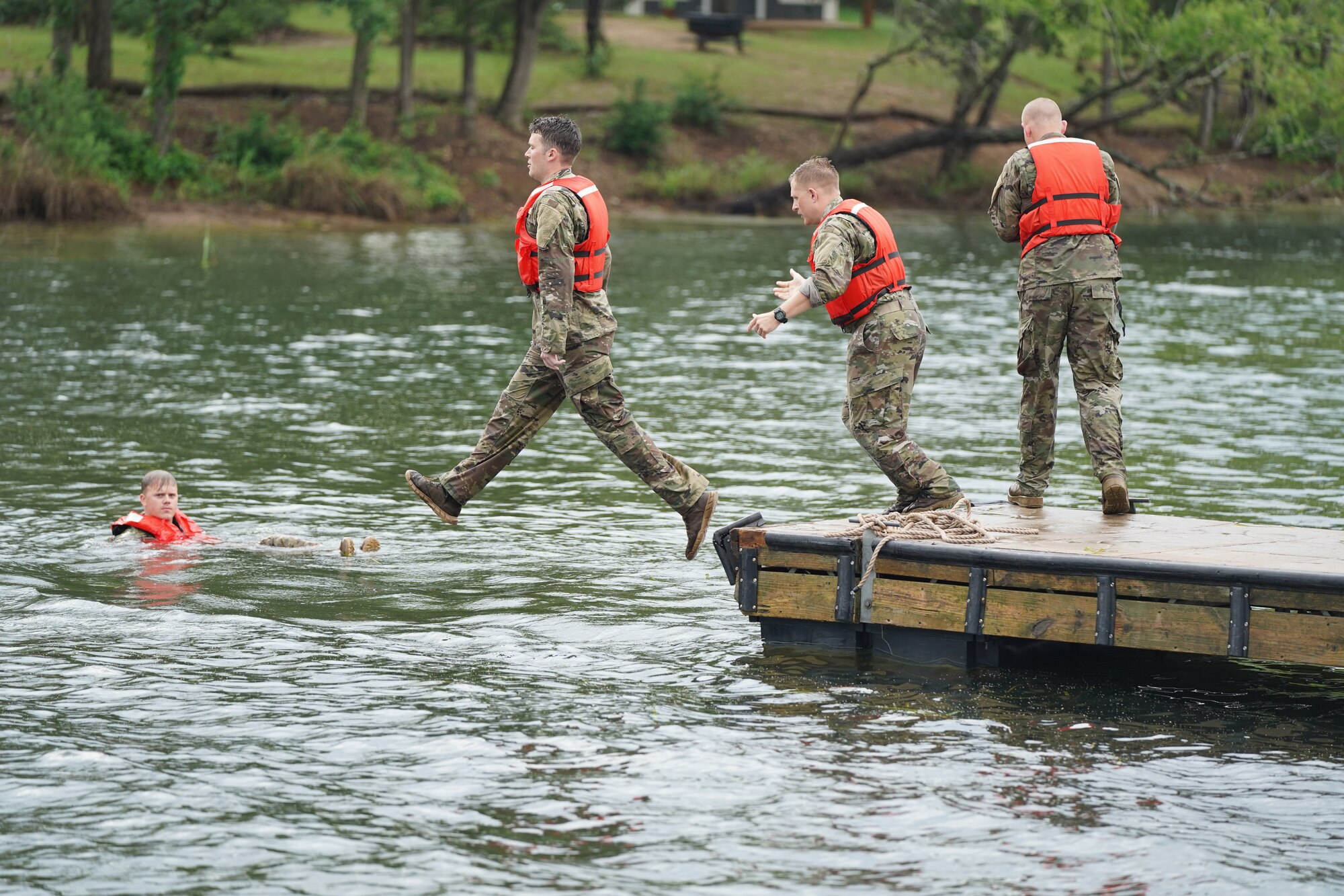 Competitors step off a lake dock into water