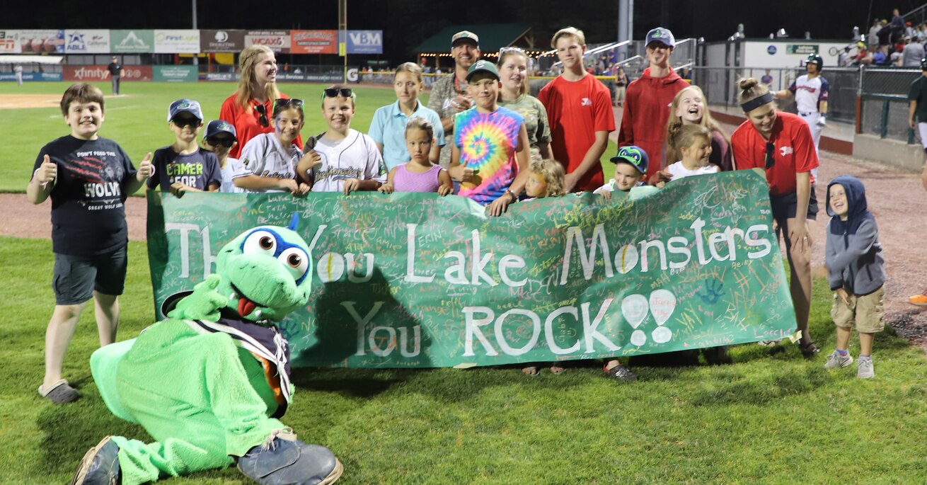 Children holding banner with Lake Monster Mascot
