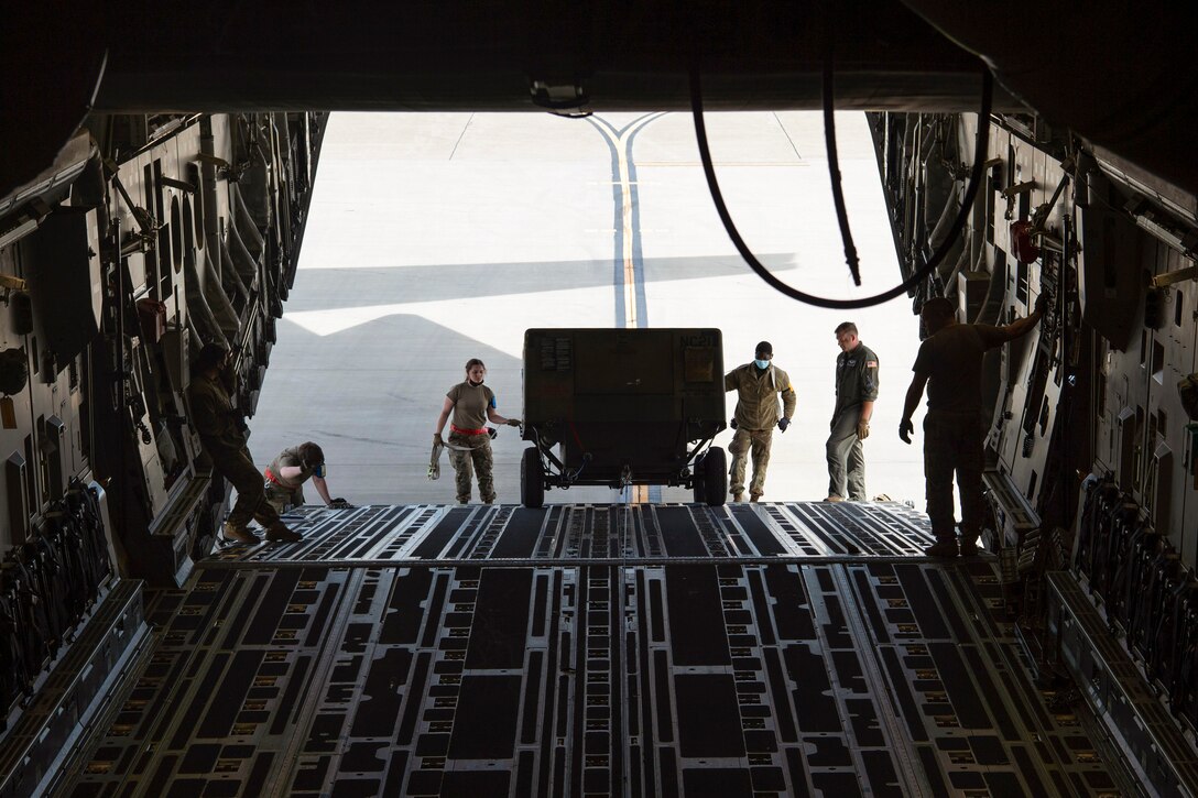 Airmen load large cargo into an aircraft.