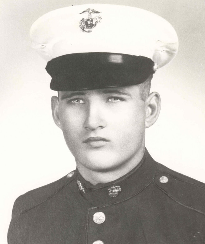 A man in a dress military uniform looks at the camera.