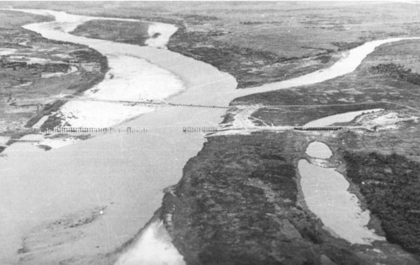 An aerial photo shows a waterway and land connected by two bridges, one of which has partially collapsed.