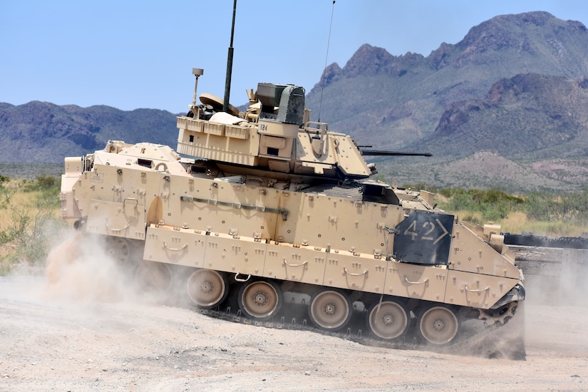 A tank rides through a desert.
