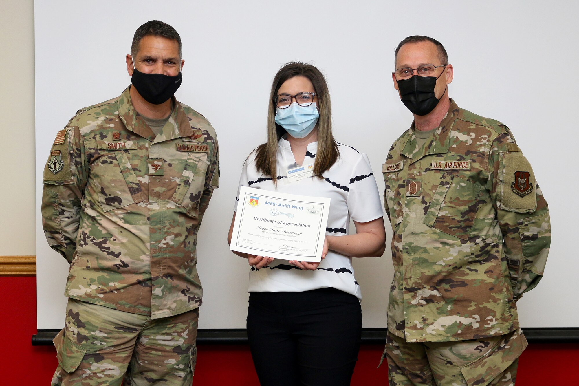 Mrs. Megan Massey-Besterman is presented a Key Spouse Certificate of Appreciation by Col. Raymond Smith, Jr., 445th Airlift Wing commander, and Chief Master Sgt. Christopher Williams, 445th AW Command Chief Master Sgt., during the 445th Airlift Wing Key Spouse Appreciation Day May 2, 2021. The spouses were treated to breakfast and C-17 Globemaster III tour. The Key Spouse Program is an official Air Force commander's program that promotes partnerships with unit leadership, volunteer Key Spouses appointed by the commander, families, Airman & Family Readiness Center and other community and helping agencies. (U.S. Air Force photo/Tech. Sgt. Joel McCullough)