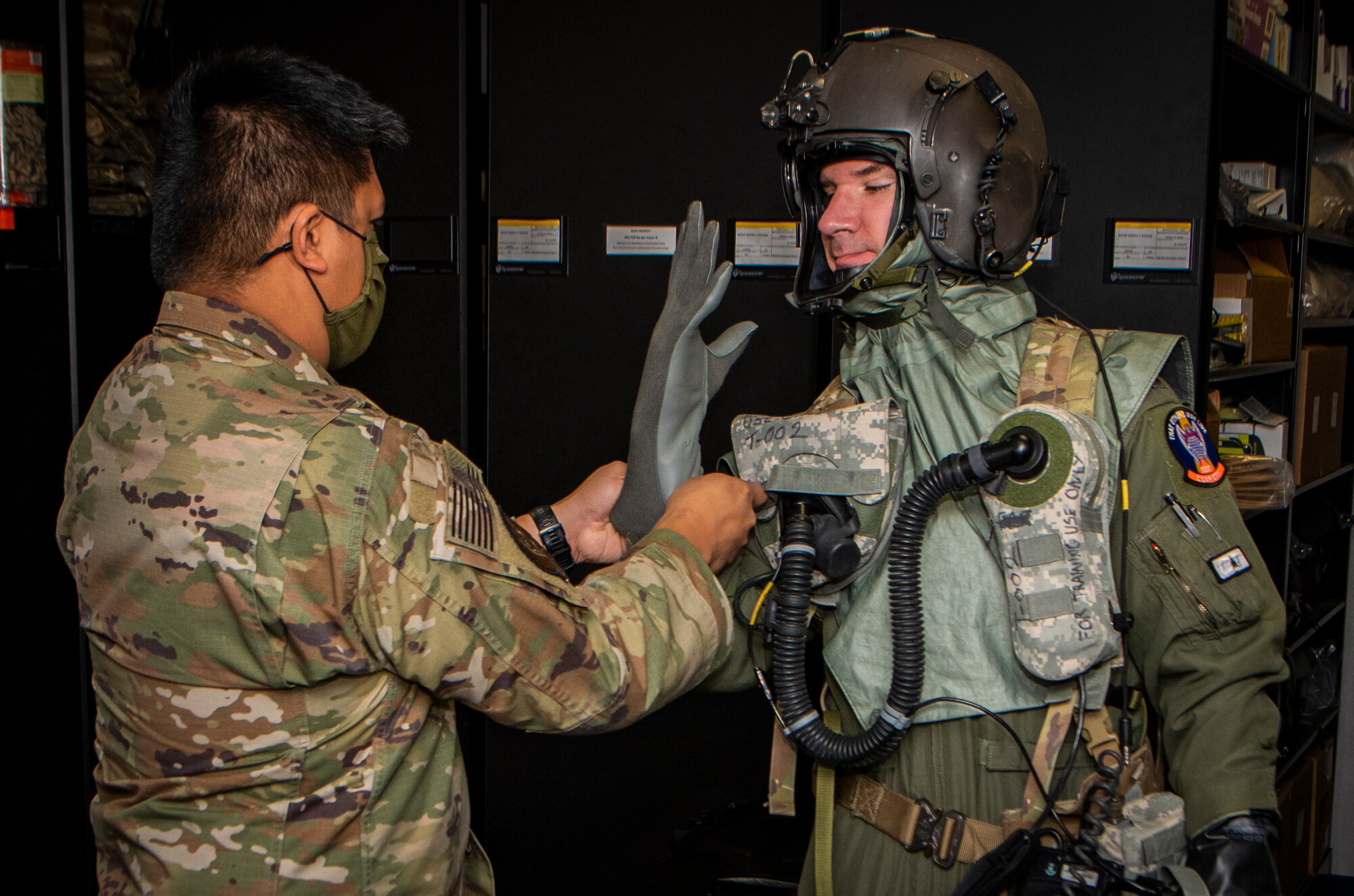 Airman assists another Airman fitting his CBRN flight gear.