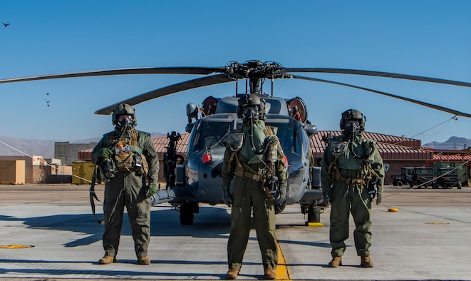 Airmen pose for photo in front of a helicopter.
