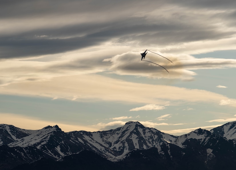 An aircraft flies near mountains.