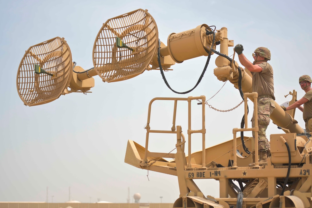 A soldier cranks open a large antenna.