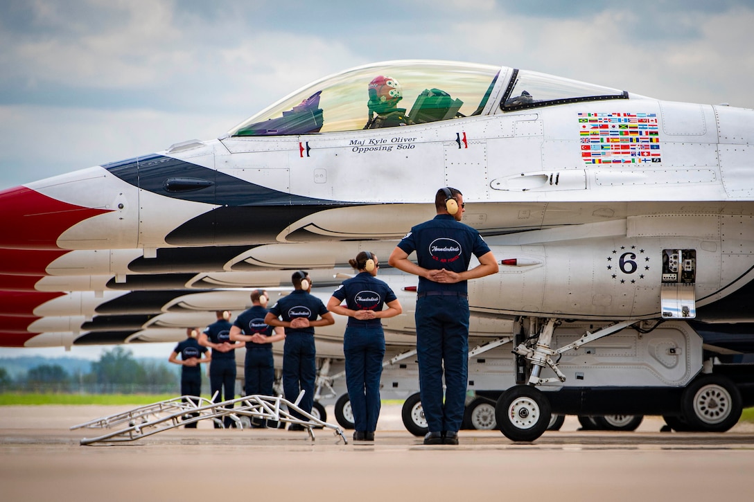 Airmen stand in formation next to a row of aircraft.