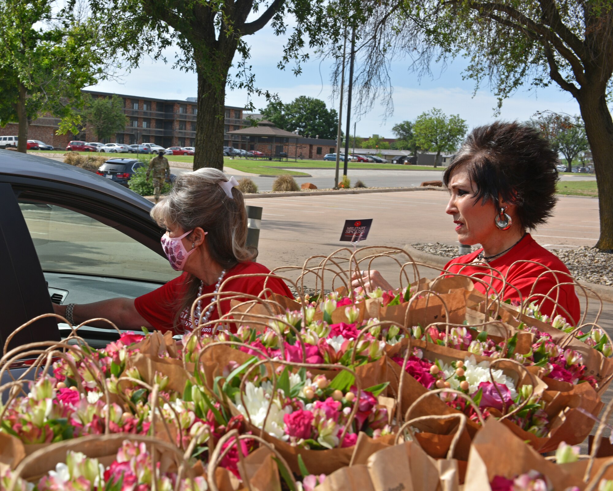 Volunteers from a local business distribute flowers to military spouses during the Military Spouse Appreciation Day Drive-Thru event at the Event Center on Goodfellow Air Force Base, Texas, May 7, 2021. The 17th Force Support Squadron partnered with a local business to recognize military spouses. (U.S. Air Force photo by Senior Airman Ashley Thrash)