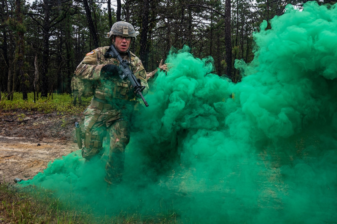 A guardsman runs through green smoke with a weapon.