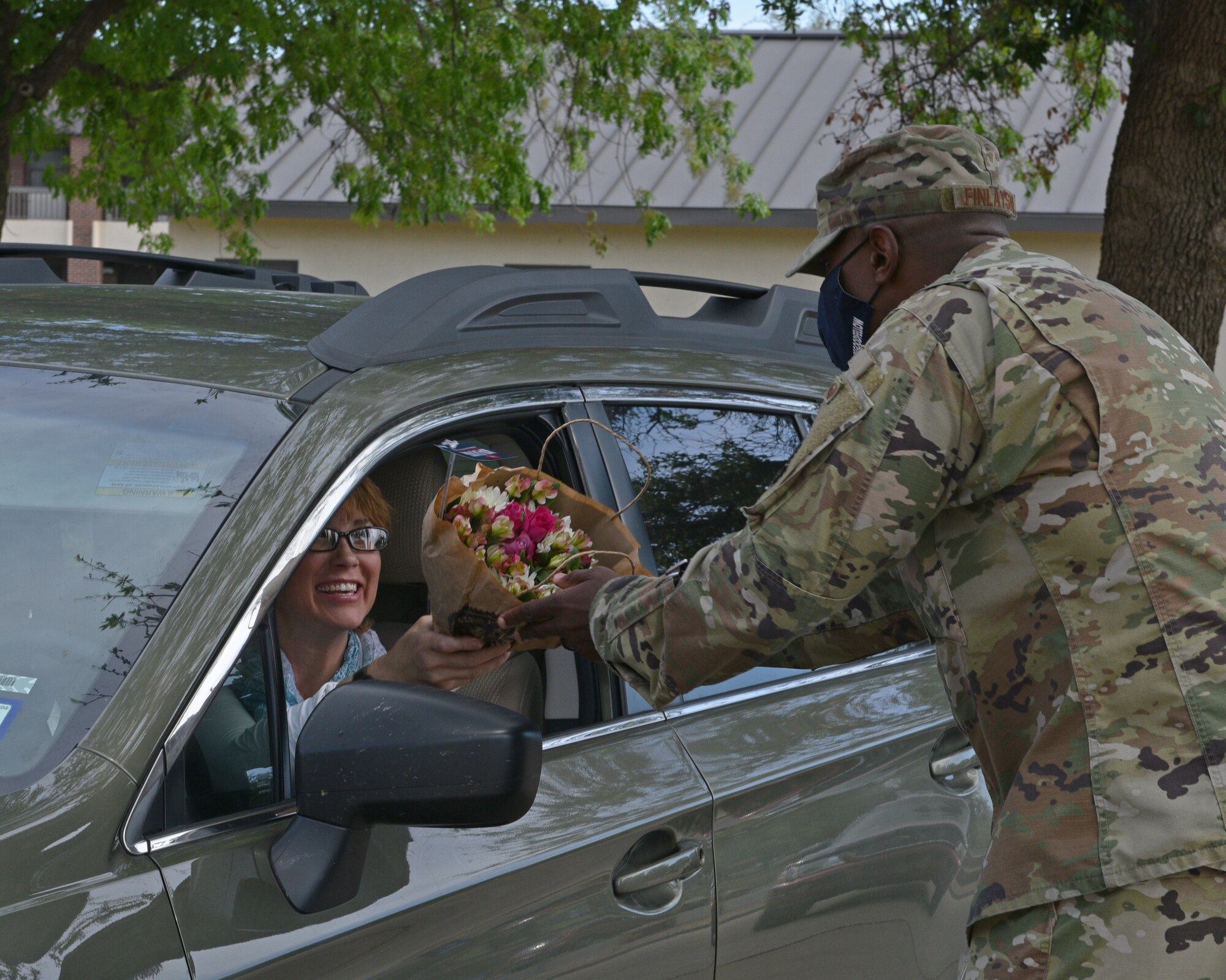 U.S. Air Force Col. James Finlayson, 17th Training Wing vice commander, hands flowers to a Goodfellow member during the Military Spouse Appreciation Day Drive-Thru event at the Event Center on Goodfellow Air Force Base, Texas, May 7, 2021. The base delivered over 800 flowers in support of all military spouses. (U.S. Air Force photo by Senior Airman Ashley Thrash)
