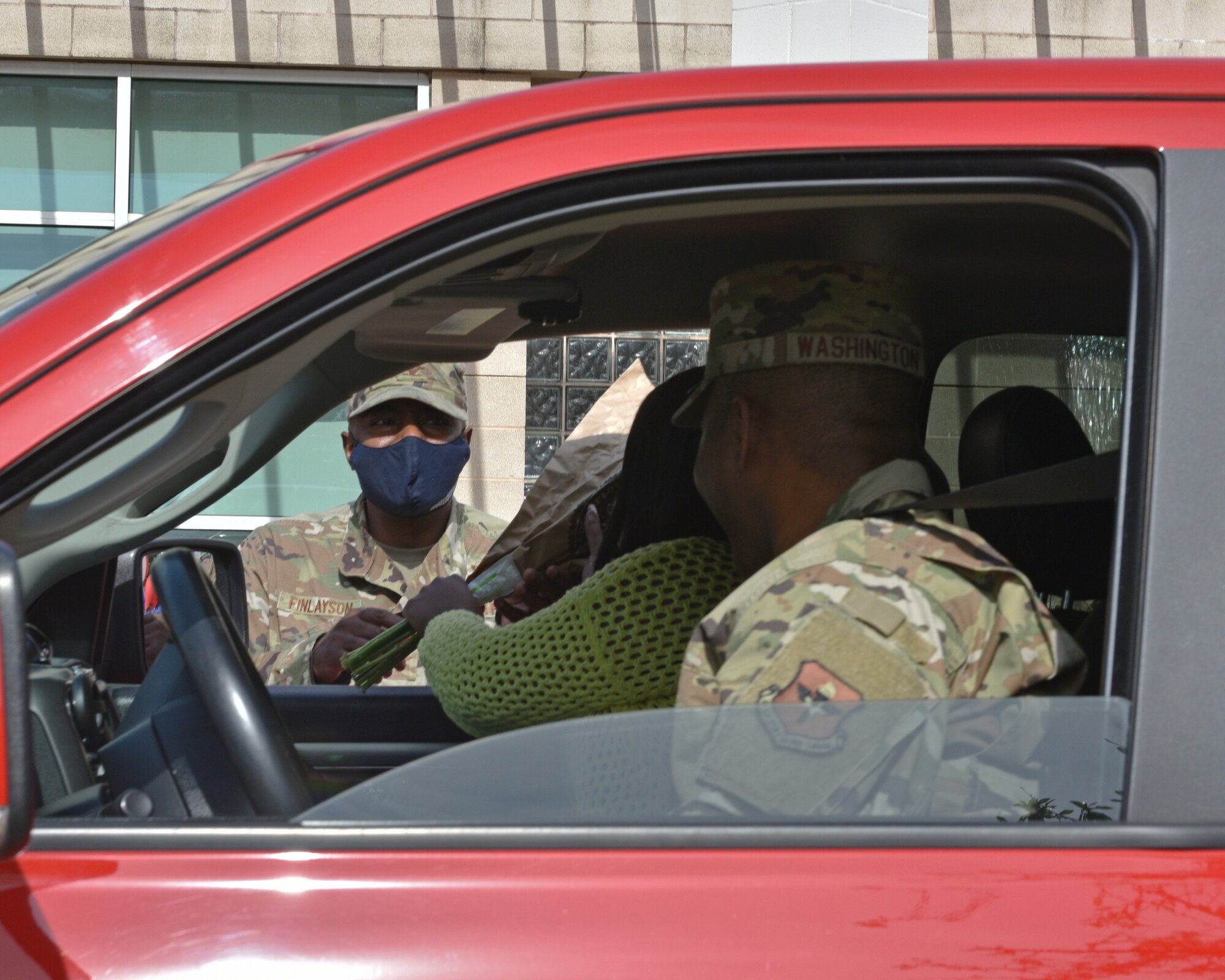 U.S. Air Force Col. James Finlayson, 17th Training Wing vice commander, hands flowers to Chief Master Sgt. Marcus Washington, 17th Medical Group superintendent, and his spouse, during the Military Spouse Appreciation Day Drive-Thru event at the Event Center on Goodfellow Air Force Base, Texas, May 7, 2021. Military spouse appreciation day gave thanks for the courage and strength of all military spouses. (U.S. Air Force photo by Senior Airman Ashley Thrash)