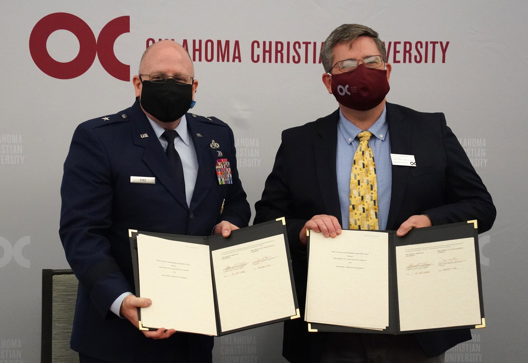 Two men holding up signed paperwork