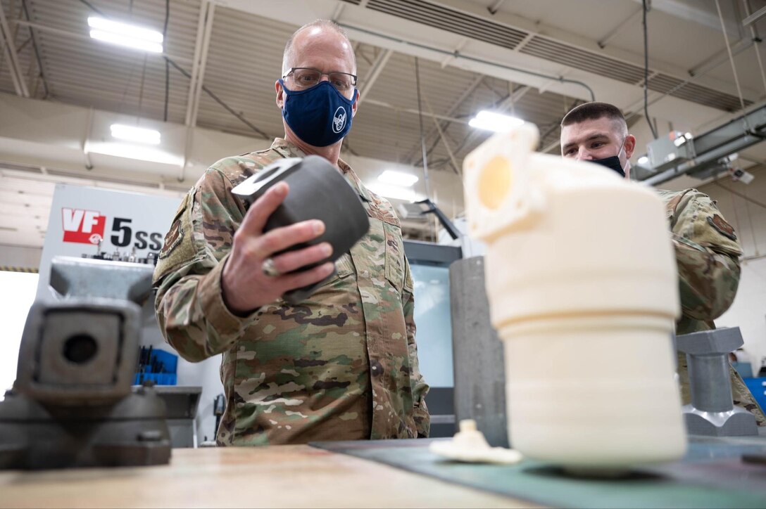 Tech. Sgt. Lance Liverman, the 28th Maintenance Squadron Additive Manufacturing Facility section chief, right, shows Maj. Gen. Mark Weatherington, the 8th Air Force and Joint-Global Strike Operations Center commander, 3D printed B-1B Lancer parts during his visit to Ellsworth Air Force Base, S.D., May 4, 2021.