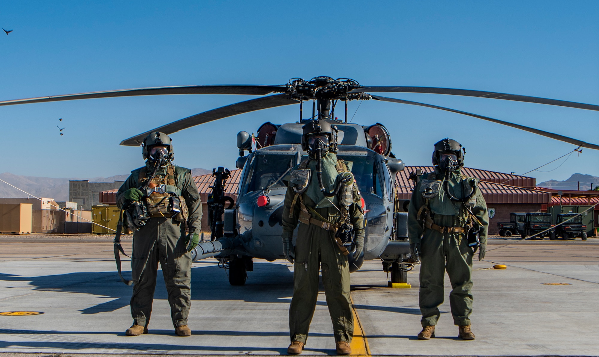 Airmen pose for photo in front of a helicopter.