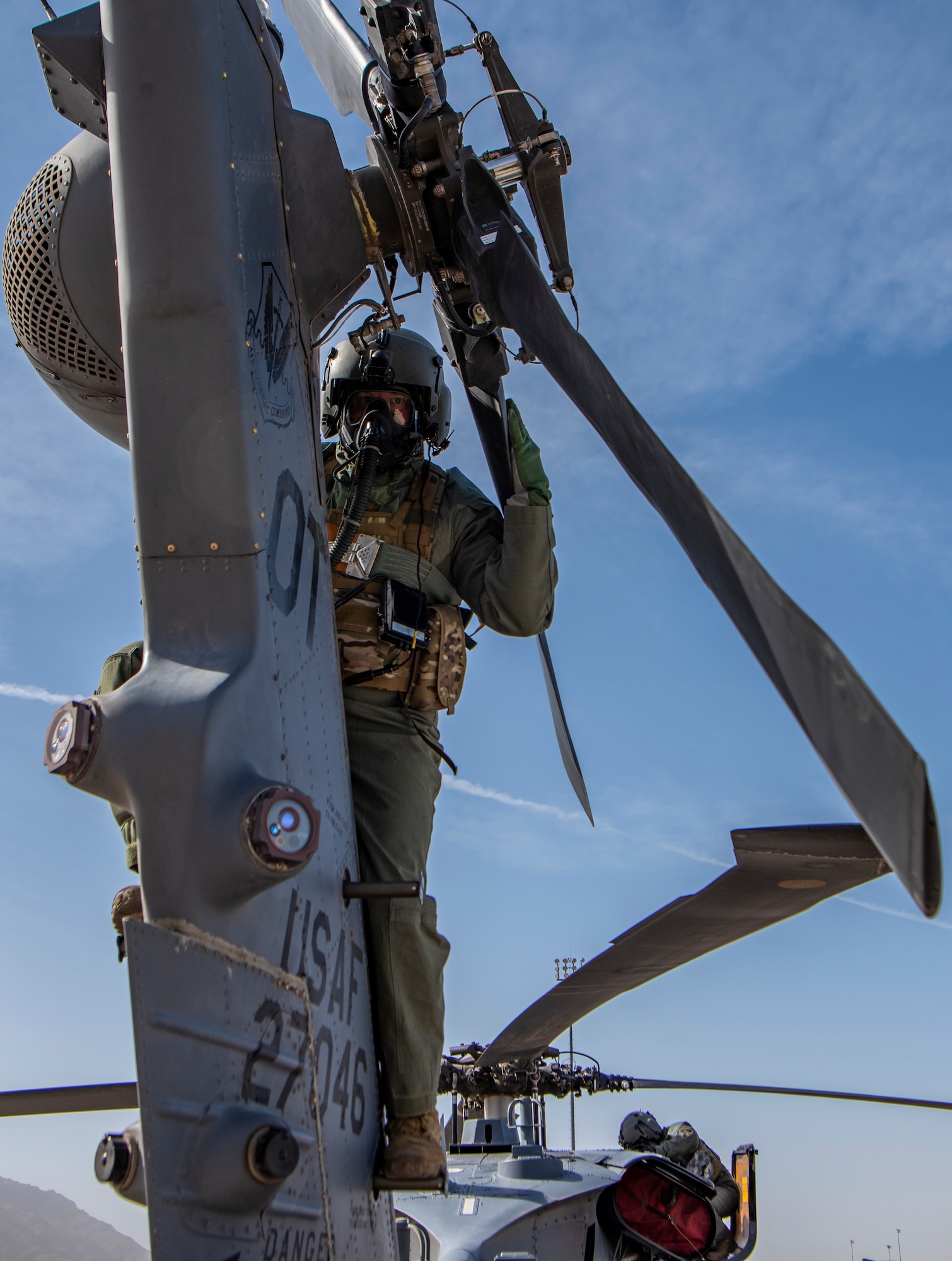 Airmen perform pre-flight checks on a helicopter.