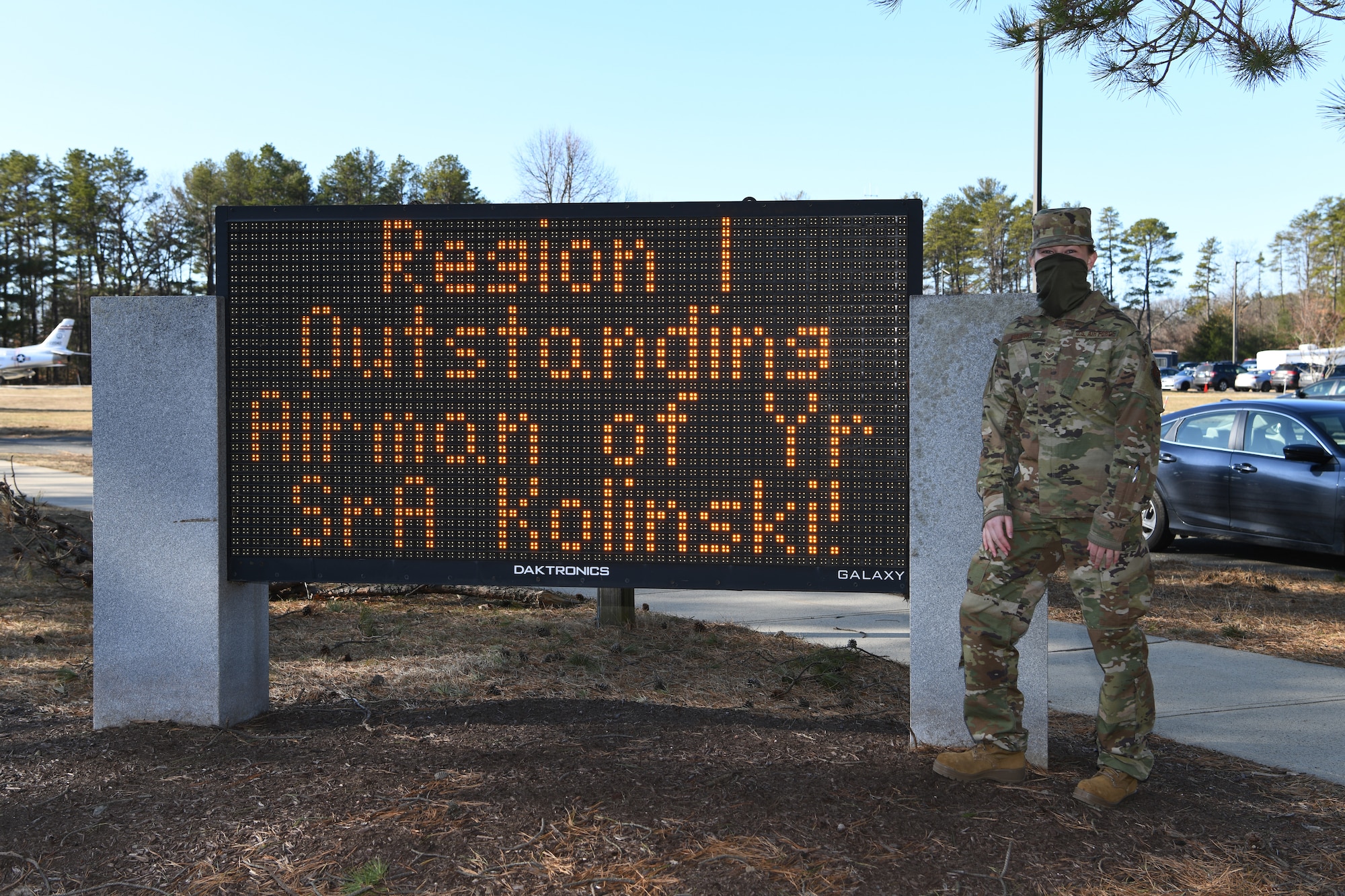Senior Airman Sara Kolinski, 104th Fighter Wing public affairs specialist, poses for a photo next to a sign on Barnes Air National Guard Base, Massachusetts, Mar. 13, 2021. Kolinski was named the Air National Guard Region One Outstanding Airman of the Year for 2020. (U.S. Air National Guard photo by Staff Sgt. Hanna Smith)