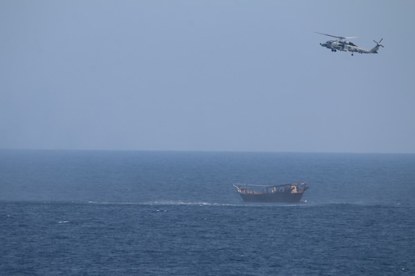 An SH-60 Sea Hawk helicopter assigned to the guided-missile cruiser USS Monterey (CG 61), not shown, flies above a stateless dhow interdicted with a shipment of illicit weapons in international waters of the North Arabian Sea.