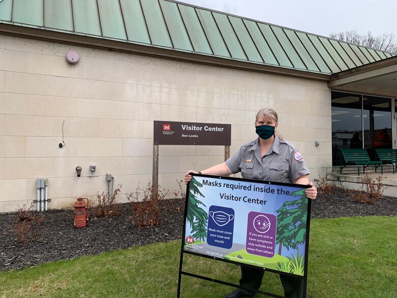 U.S. Army Corps of Engineer's Soo Area Office Chief Park Ranger Michelle Briggs posts a COVID-19 sign for the Soo Locks Visitor Center opening on May 7, 2021 in Sault Ste. Marie, Mich.