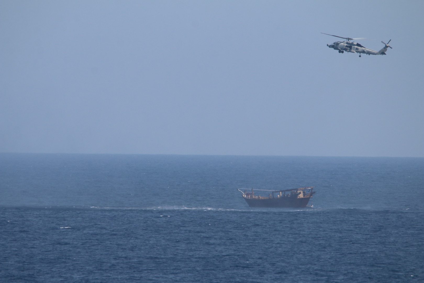 210506-N-NO146-1004 NORTH ARABIAN SEA (May 6, 2021)  An SH-60 Seahawk helicopter assigned to the guided-missile cruiser USS Monterey (CG 61)(not shown) flies above a stateless dhow interdicted with a shipment of illicit weapons in international waters of the North Arabian Sea on May 6-7. Maritime security operations, as conducted by the U.S. Fifth Fleet, entail routine patrols to determine pattern of life in the maritime as well as to enhance mariner-to-mariner relations. These operations reassure allies and partners and preserve freedom of navigation and free flow of commerce (U.S. Navy Photo)