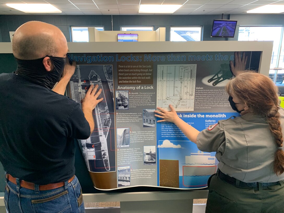 U.S. Army Corps of Engineer's Soo Area Office Chief Park Ranger Michelle Briggs and helper add to an exhibit for the Soo Locks Visitor Center opening on May 6, 2021 in Sault Ste. Marie, Mich.