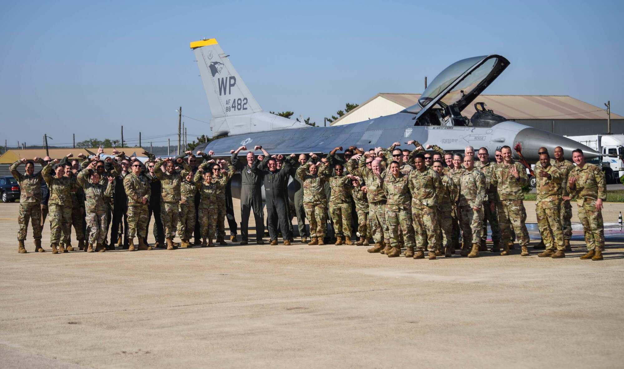 group of people posing in front of a jet.
