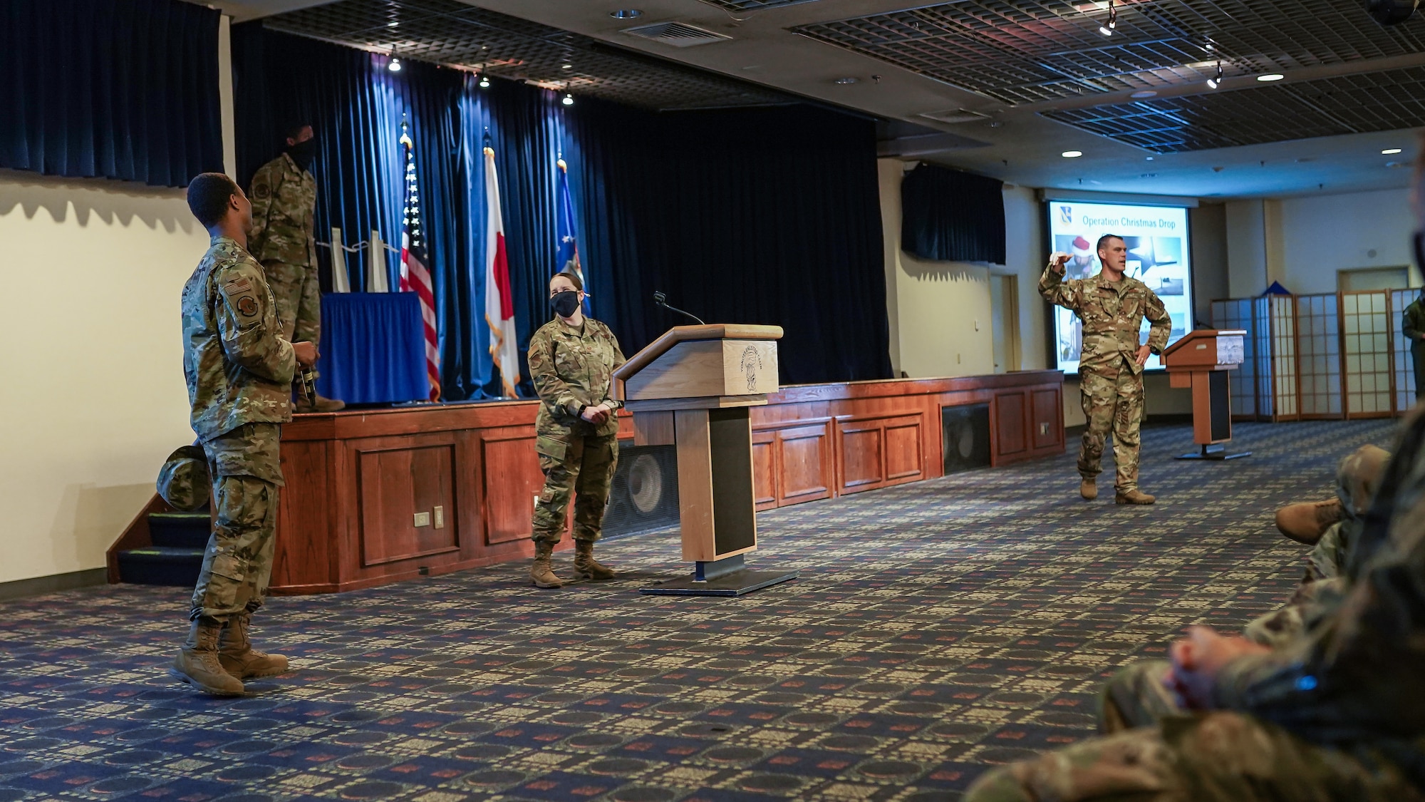 Colonel Campbell and an Airman speak to a crowd in the Enlisted Club