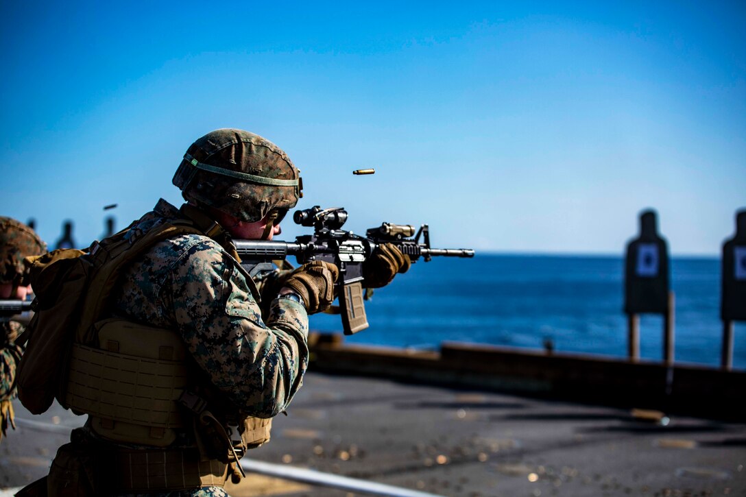 Marines fire at targets on the deck of a ship.