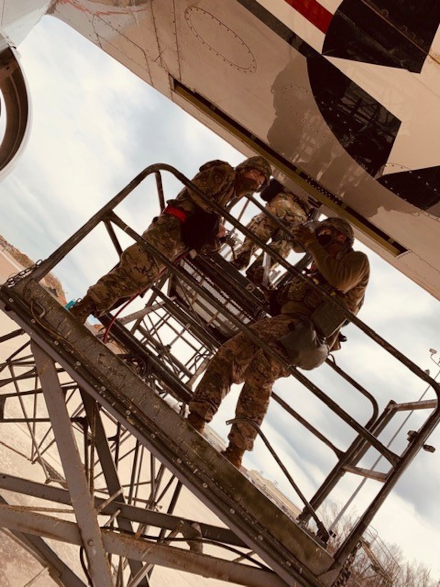 Two men working on wing of airplane