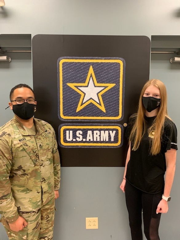 A man stands on the left and a young woman on the right in front of two flags.