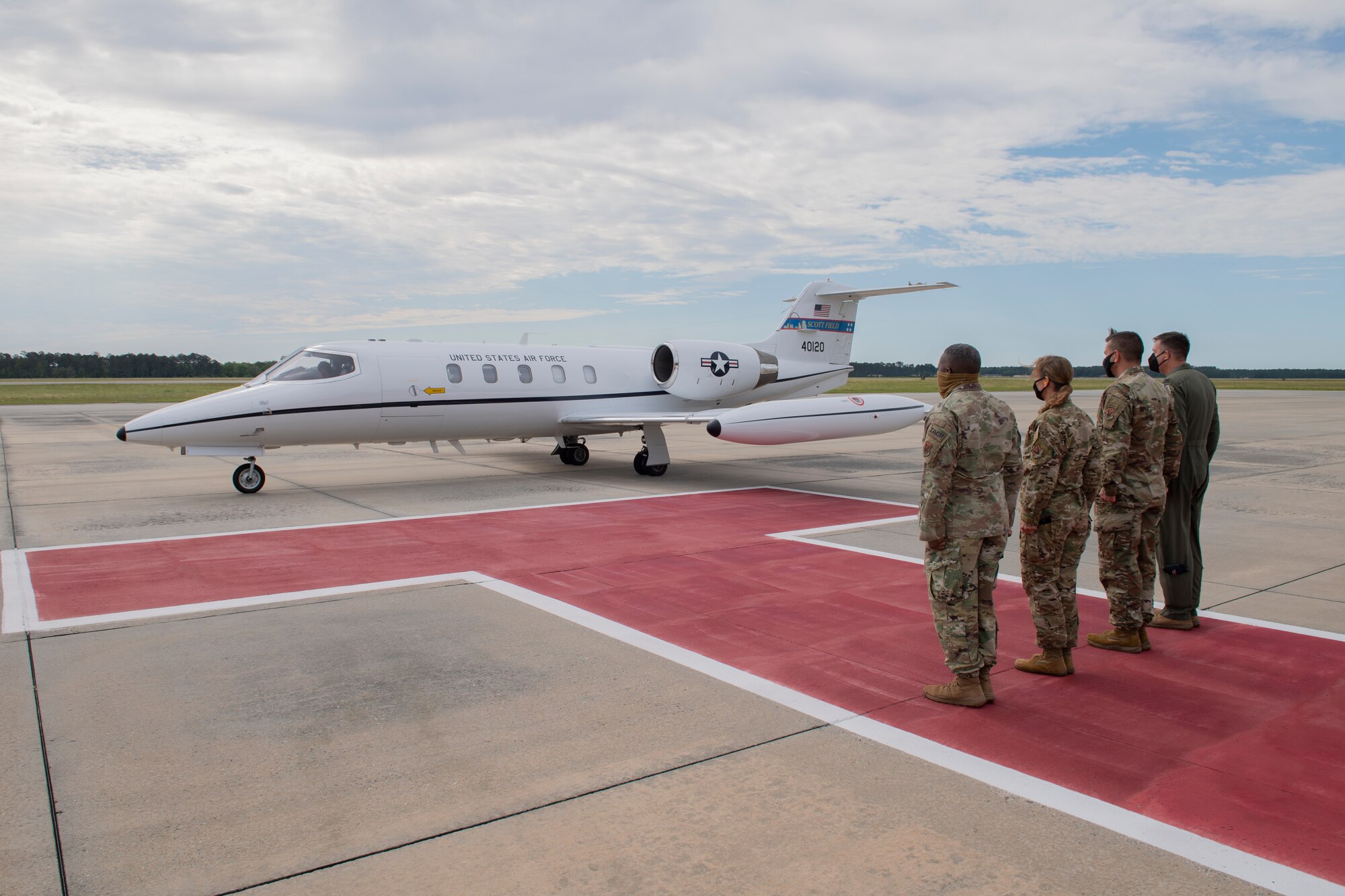 A photo of four Airman standing at attention in front of an airplane.